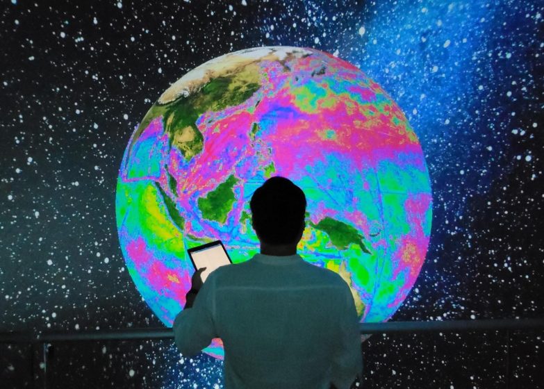 A picture of a person's silhouette in front of a glowing, multicolored globe