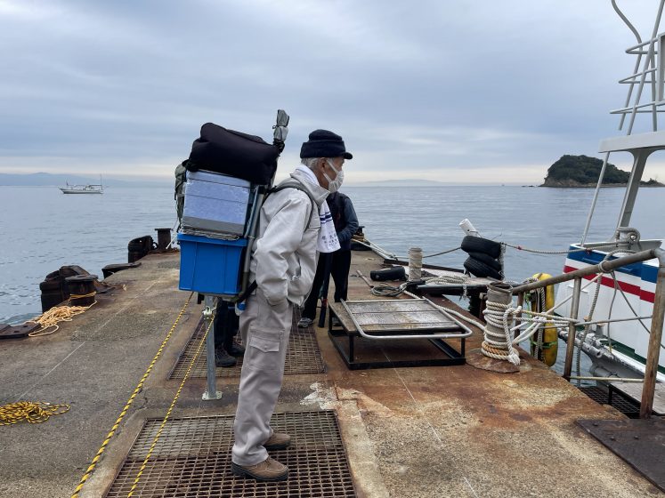 A person standing on a dock with a large container on their back