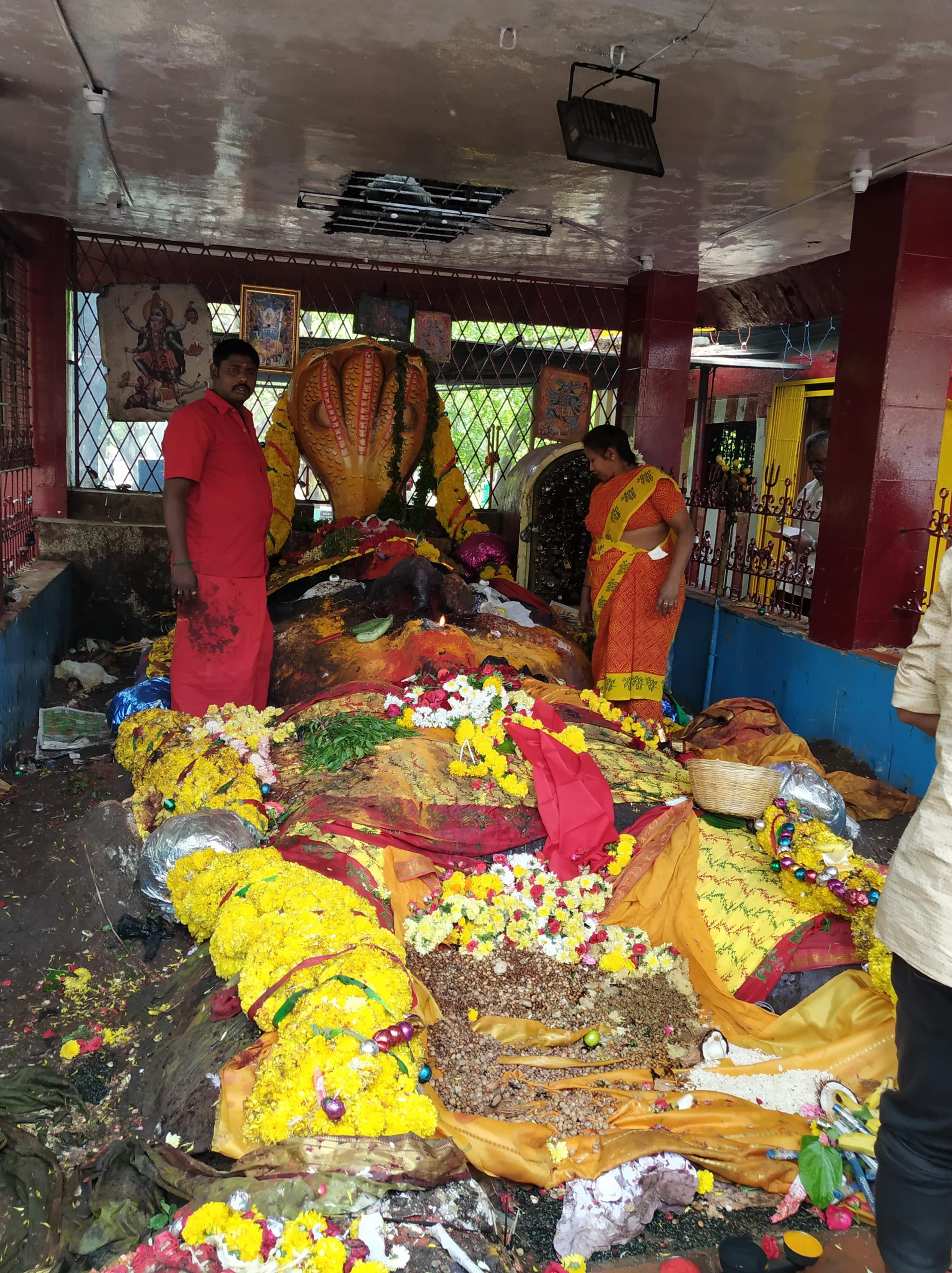 A group of people in a room with a large statue and a table full of food laid before it