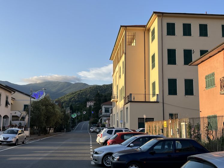 A street with multi-story buildings and cars parked along the road