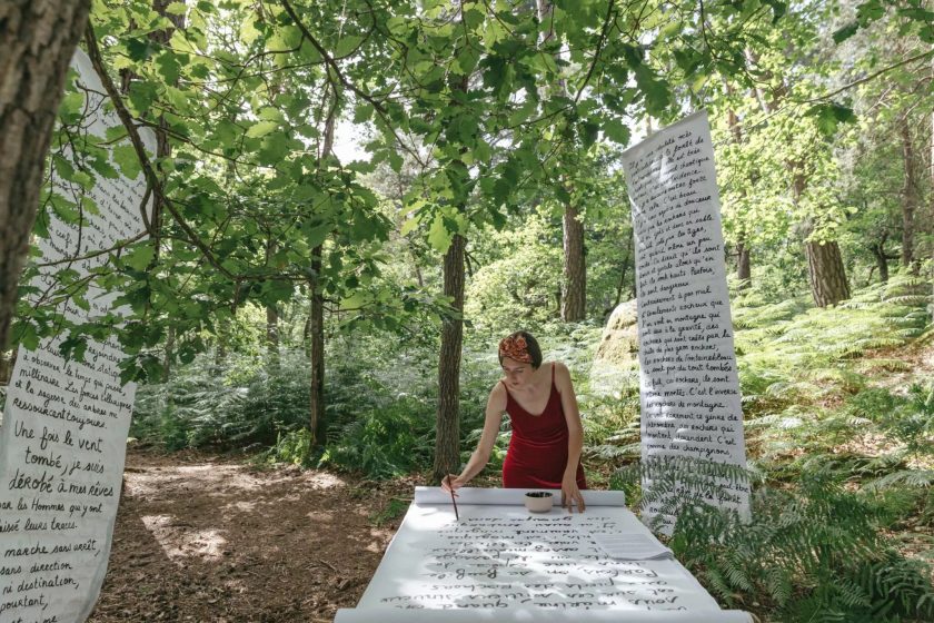 A person writing on a table in black paint in the woods