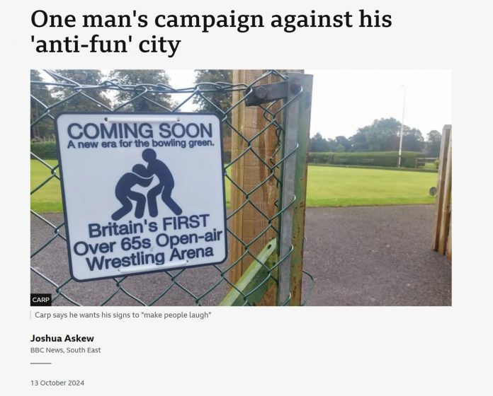 A news article stating "One man's campaign against his 'anti-fun' city with a picture of a sign "Coming Soon: A new era for the bowling green. Britain's first over 65s open-air wrestling arena" in front of a park