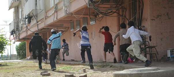 A group of children running outside beside a building