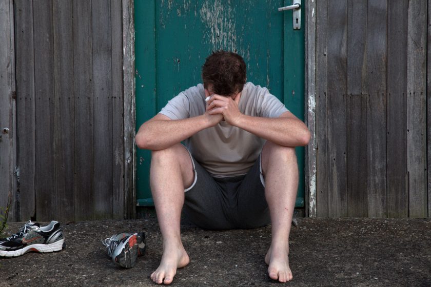 A person sitting on the ground with his head in his hands