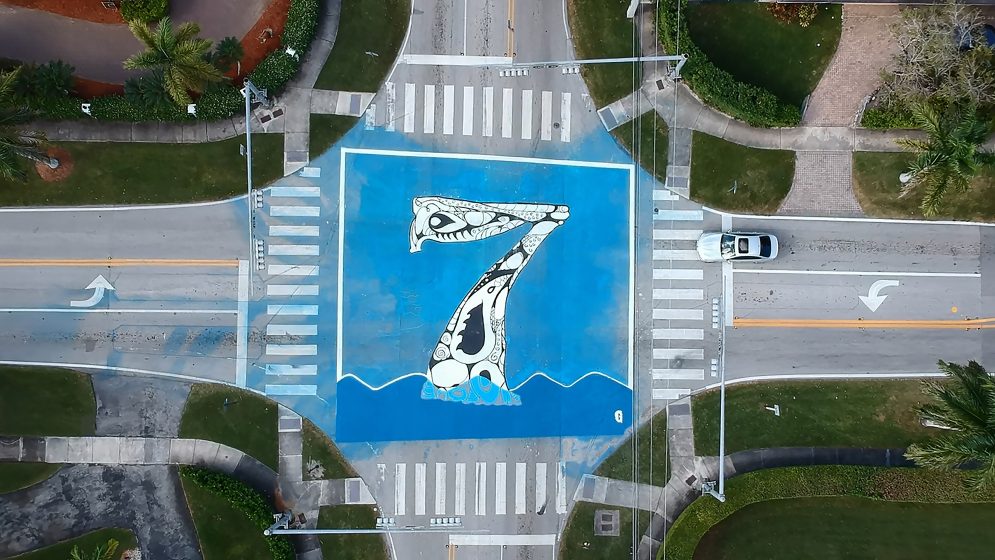 An aerial view of an intersection with a giant blue seven painted on it