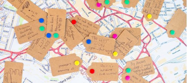 A group of brown tags with colorful pins on top of a map