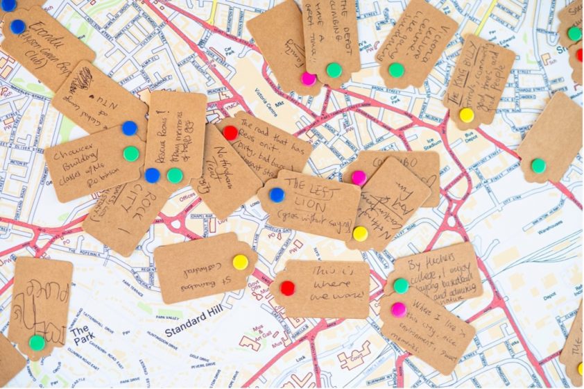 A group of brown tags with colorful pins on top of a map