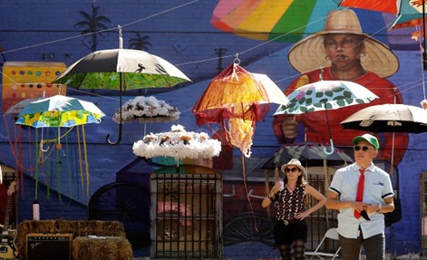 Two people standing underneath painted umbrellas hanging from wires