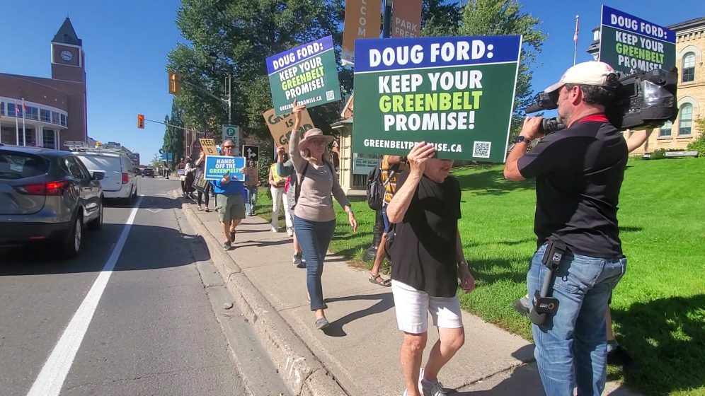 A picture of people holding signs, walking along a sidewalk