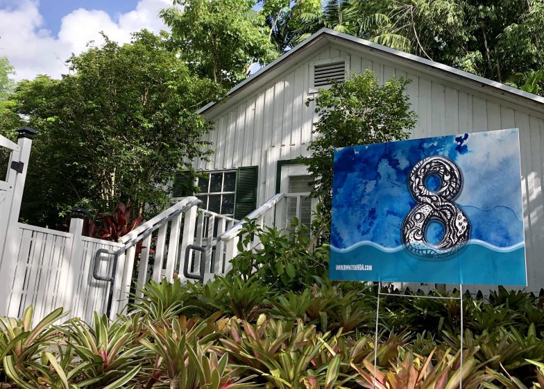 A picture of a house with a yard sign with a blue eight painted on it