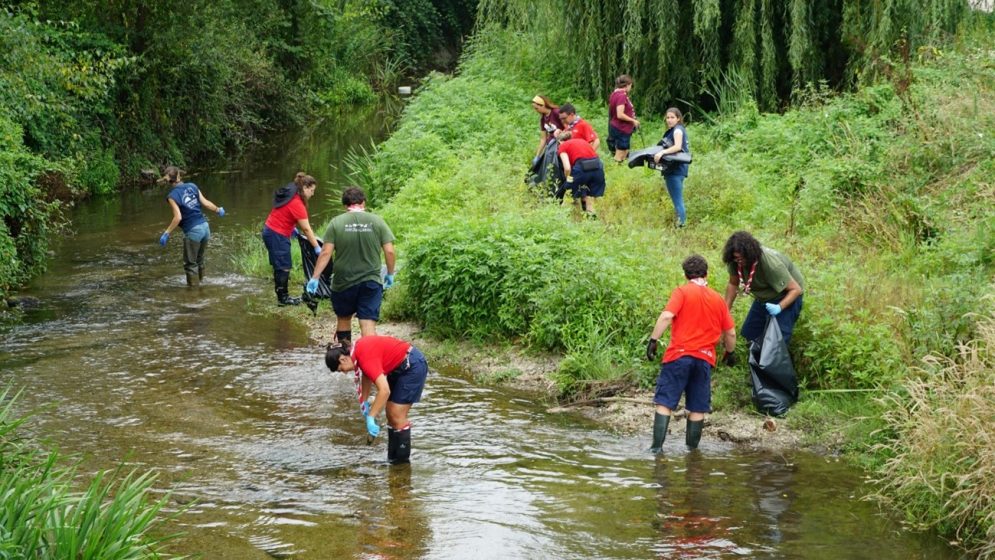 A group of people in a stream picking up trash