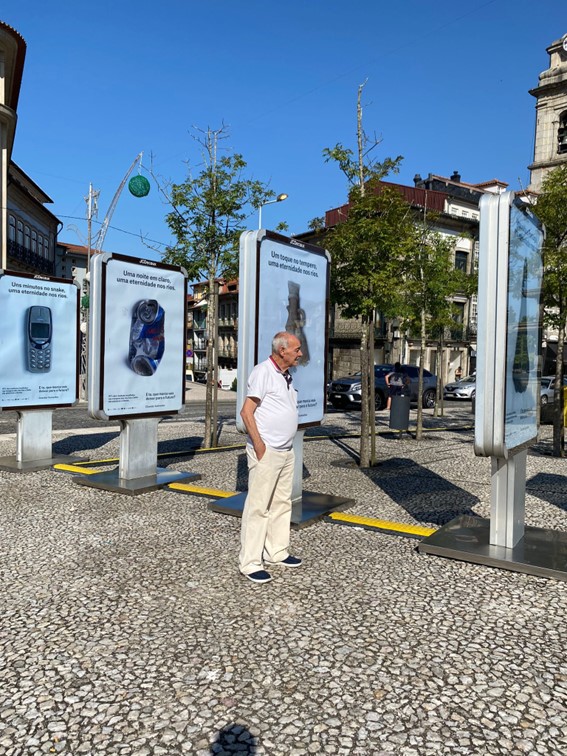 A man standing in front of a row of signs with different pieces of garbage on them on the sidewalk