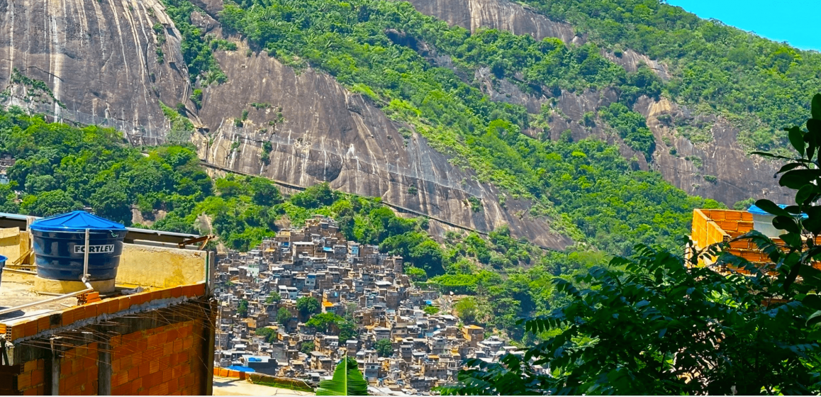 A picture of a city with a large, forested cliff behind it