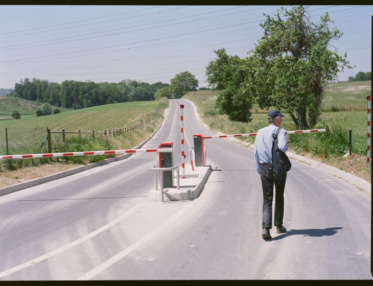 A picture of a person walking down a paved road with traffic gates in the distance