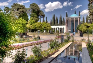 A building with columns and a fountain in front of it with foliage