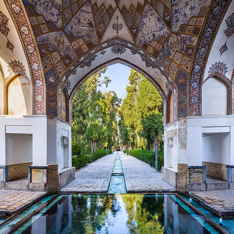 A pavilion with a pool of water and a garden beyond 